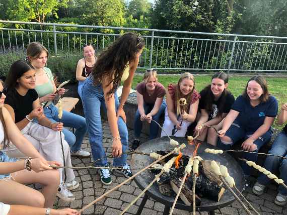 Schülerinnen sitzen am Lagerfeuer