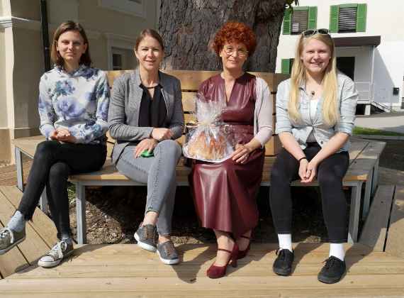 Zwei Schülerinnen sitzen mit Frau Prof. Hermann und Frau Inspektorin auf einer Bank