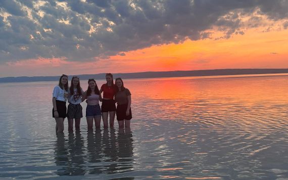 Schülerinnen stehen bei Sonnenuntergang im Neusiedlersee