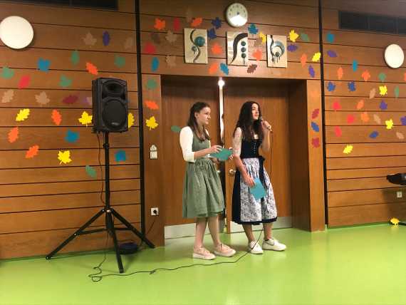 zwei Schülerinnen stehen mit Mikrofon auf der Bühne