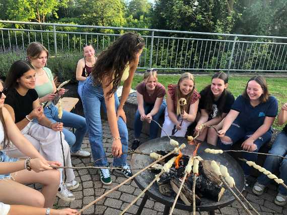 Schülerinnen sitzen am Lagerfeuer