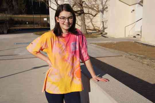Schülerin präsentiert ihr gelb rot gebatiktes Pitz T-Shirt
