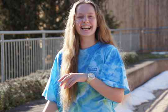 Schülerin lächelt in die Kamera im blau gebatikten Pitz T-Shirt