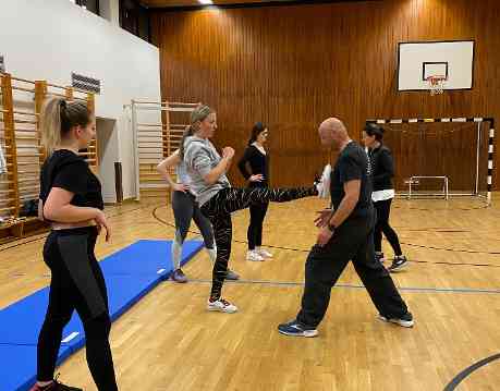 eine Schülerin übt einen Verteidigungsgriff mit dem Lehrer