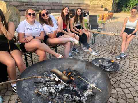 Schülerinnen sitzen am Lagerfeuer