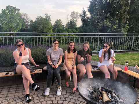 Schülerinnen sitzen am Lagerfeuer