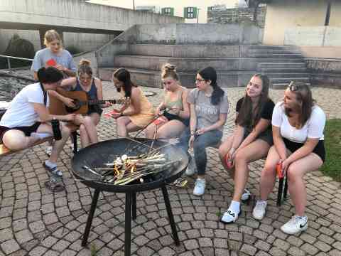 Schülerinnen sitzen am Lagerfeuer